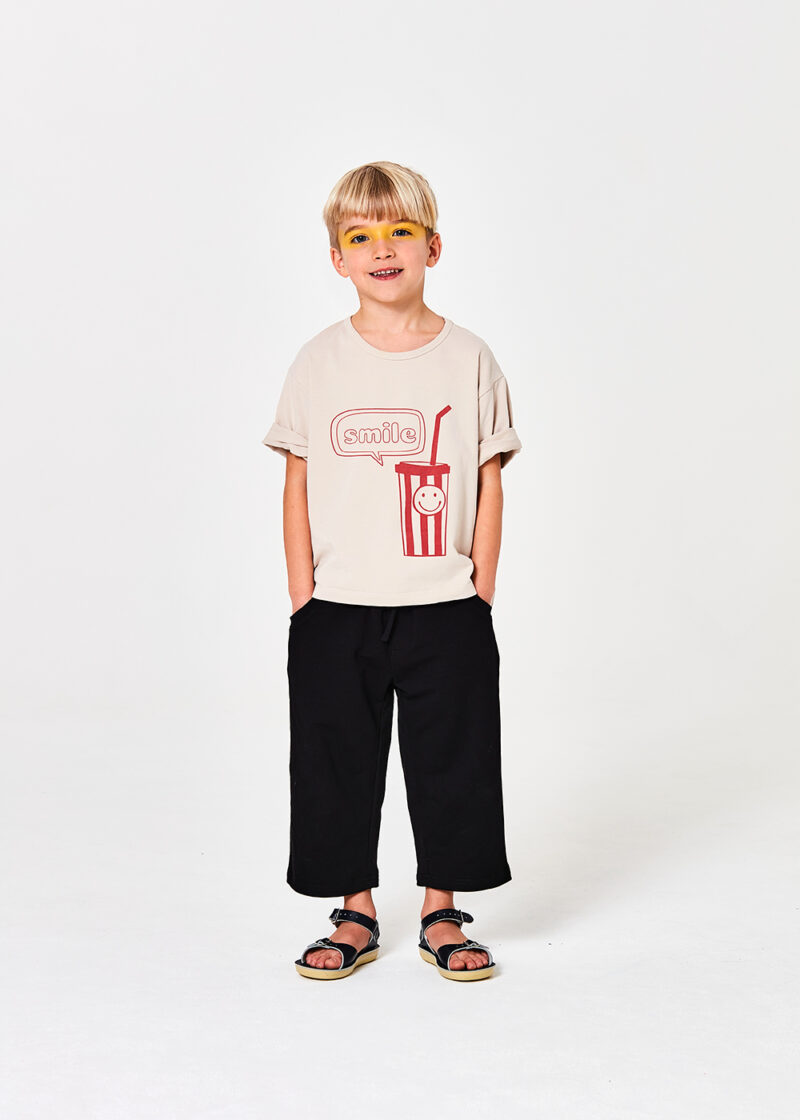 beżowy t-shirt dziecięcy, z krótkim rekawem, koszulka dla dziecka bawełniana z nadrukiem, kremowa, czarne dzianinowe spodnie dziecięce, bermudy, spodnie długość 3/4